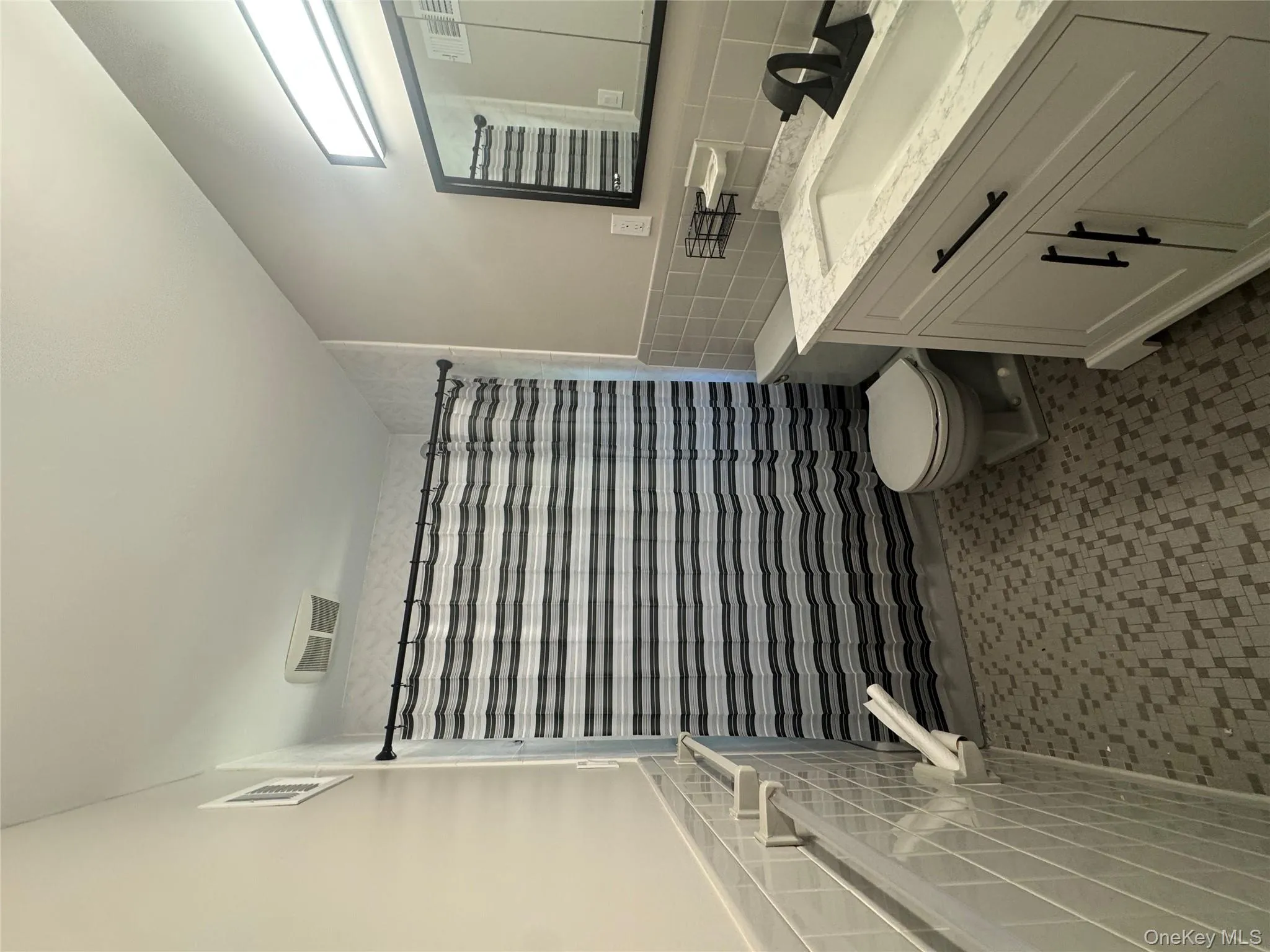Bathroom featuring a shower with shower curtain, tile walls, vanity, and a wainscoted wall Bathroom featuring a shower with shower curtain, tile walls, vanity, and a wainscoted wall