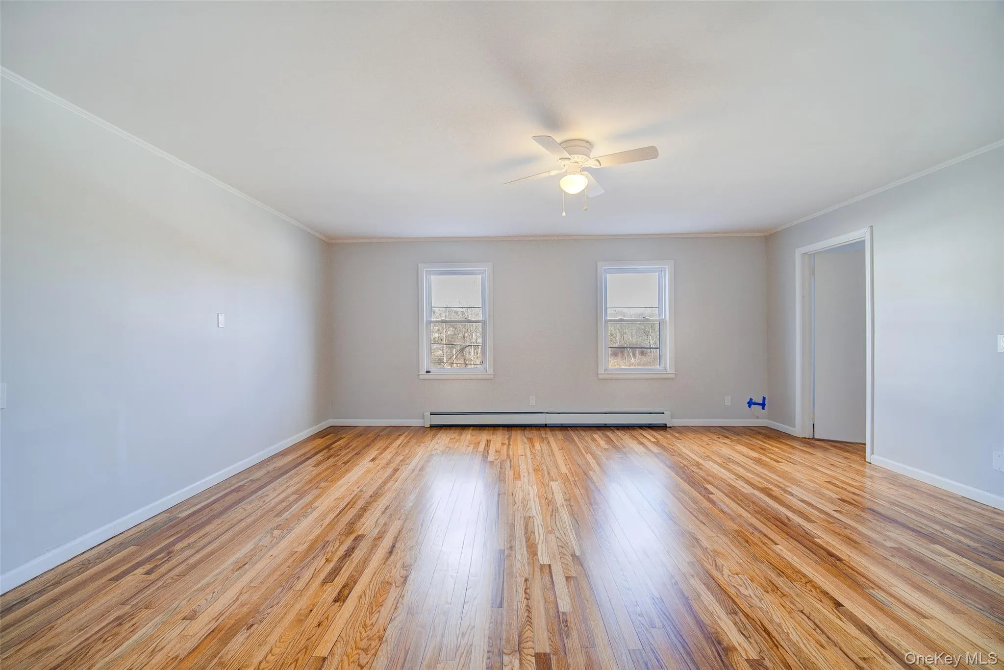 Living room with light wood-style flooring, ceiling fan, crown molding, and a baseboard heater. Living room with light wood-style flooring, ceiling fan, crown molding, and a baseboard heater.