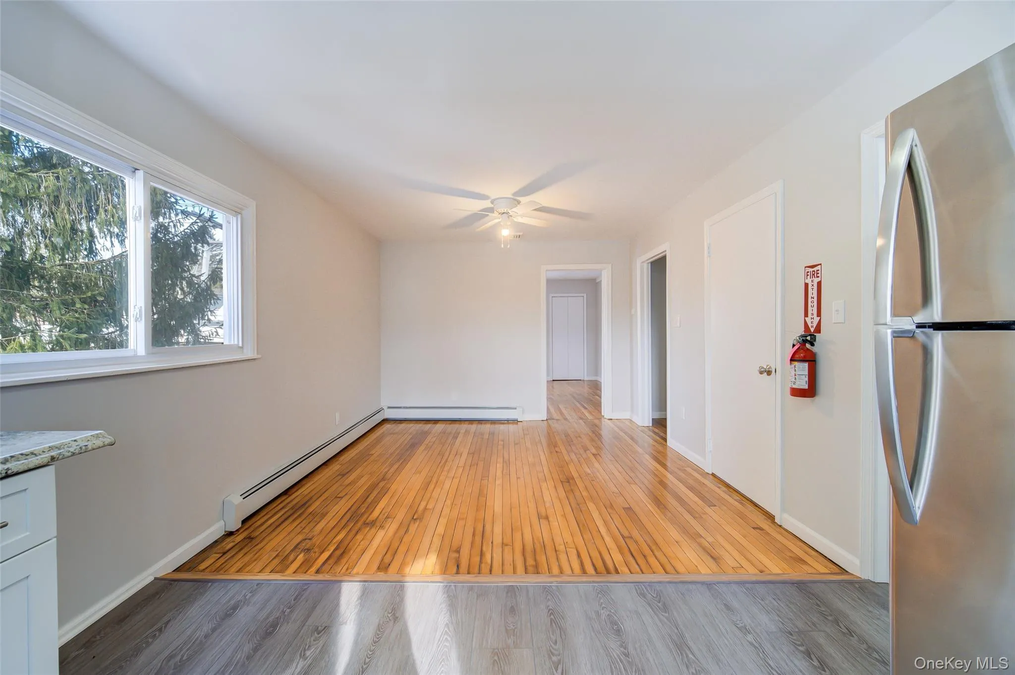 Dining area off of kitchen featuring light wood-style floors, baseboard heating, and ceiling fan Dining area off of kitchen featuring light wood-style floors, baseboard heating, and ceiling fan