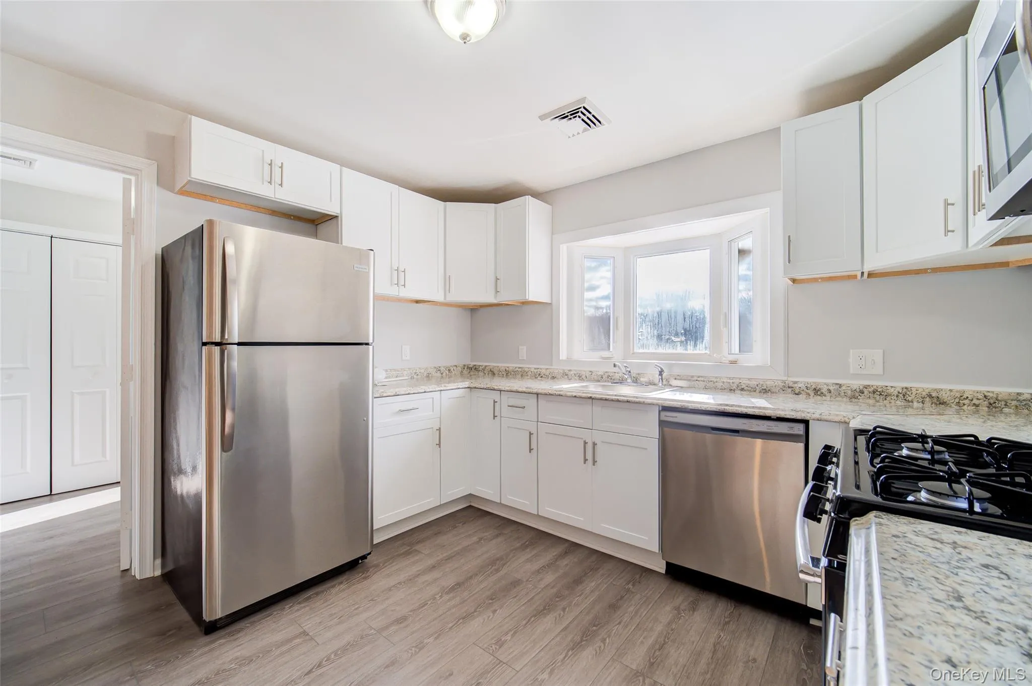 Kitchen featuring appliances with stainless steel finishes, white cabinetry, and light wood-style floors Kitchen featuring appliances with stainless steel finishes, white cabinetry, and light wood-style floors