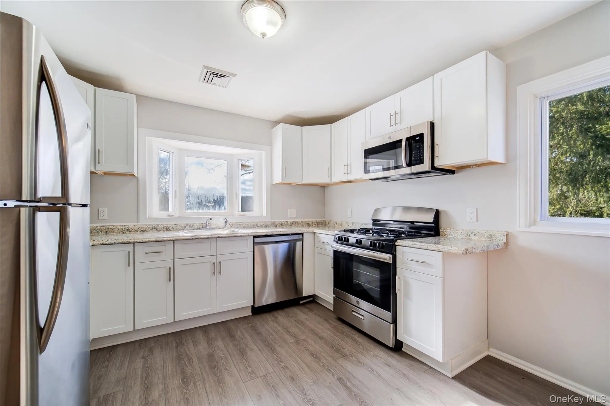 Kitchen featuring appliances with stainless steel finishes, white cabinets, and light stone counters Kitchen featuring appliances with stainless steel finishes, white cabinets, and light stone counters