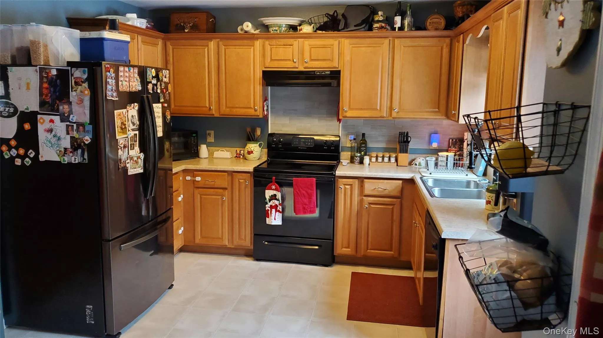 Kitchen featuring black appliances, light countertops, brown cabinetry, and decorative backsplash Kitchen featuring black appliances, light countertops, brown cabinetry, and decorative backsplash