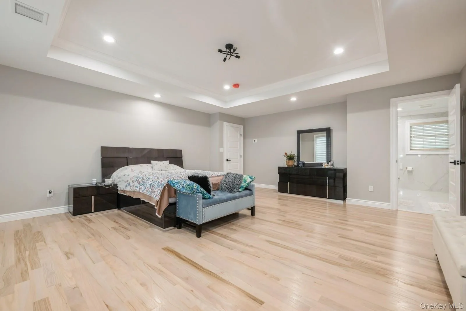 Bedroom with recessed lighting, light wood finished floors, and a tray ceiling Bedroom with recessed lighting, light wood finished floors, and a tray ceiling