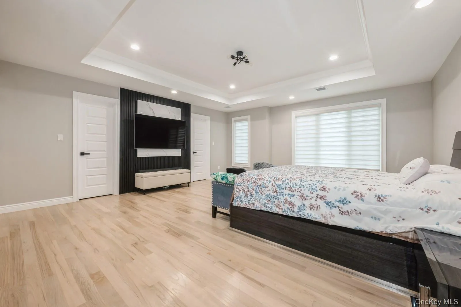Bedroom featuring light wood-type flooring, recessed lighting, and a tray ceiling Bedroom featuring light wood-type flooring, recessed lighting, and a tray ceiling