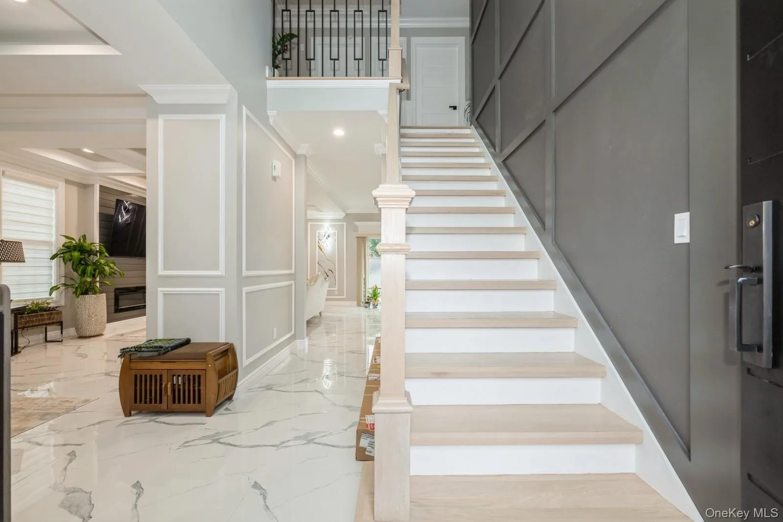 Stairway with marble tiled flooring, a decorative wall, ornamental molding, and recessed lighting Stairway with marble tiled flooring, a decorative wall, ornamental molding, and recessed lighting
