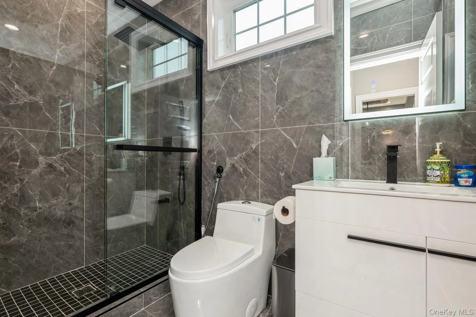 Bathroom with vanity, a marble finish shower, and tile walls Bathroom with vanity, a marble finish shower, and tile walls