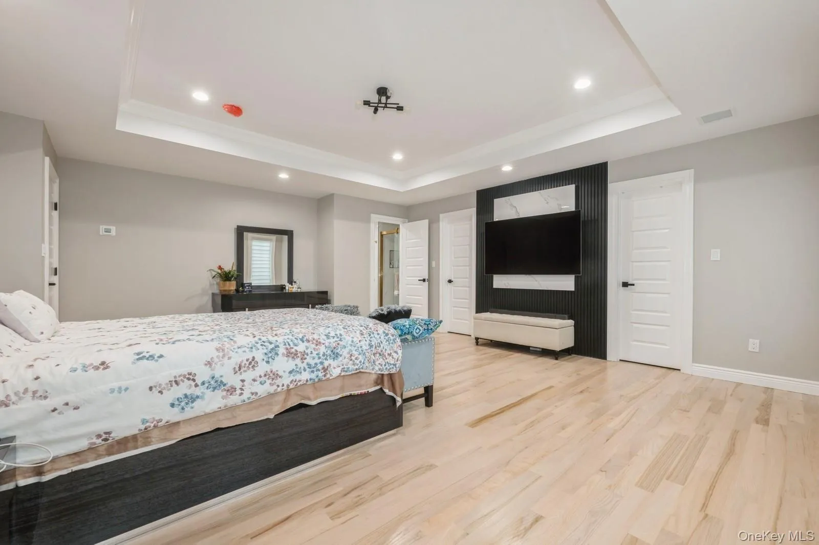 Bedroom featuring light wood finished floors, recessed lighting, and a raised ceiling Bedroom featuring light wood finished floors, recessed lighting, and a raised ceiling