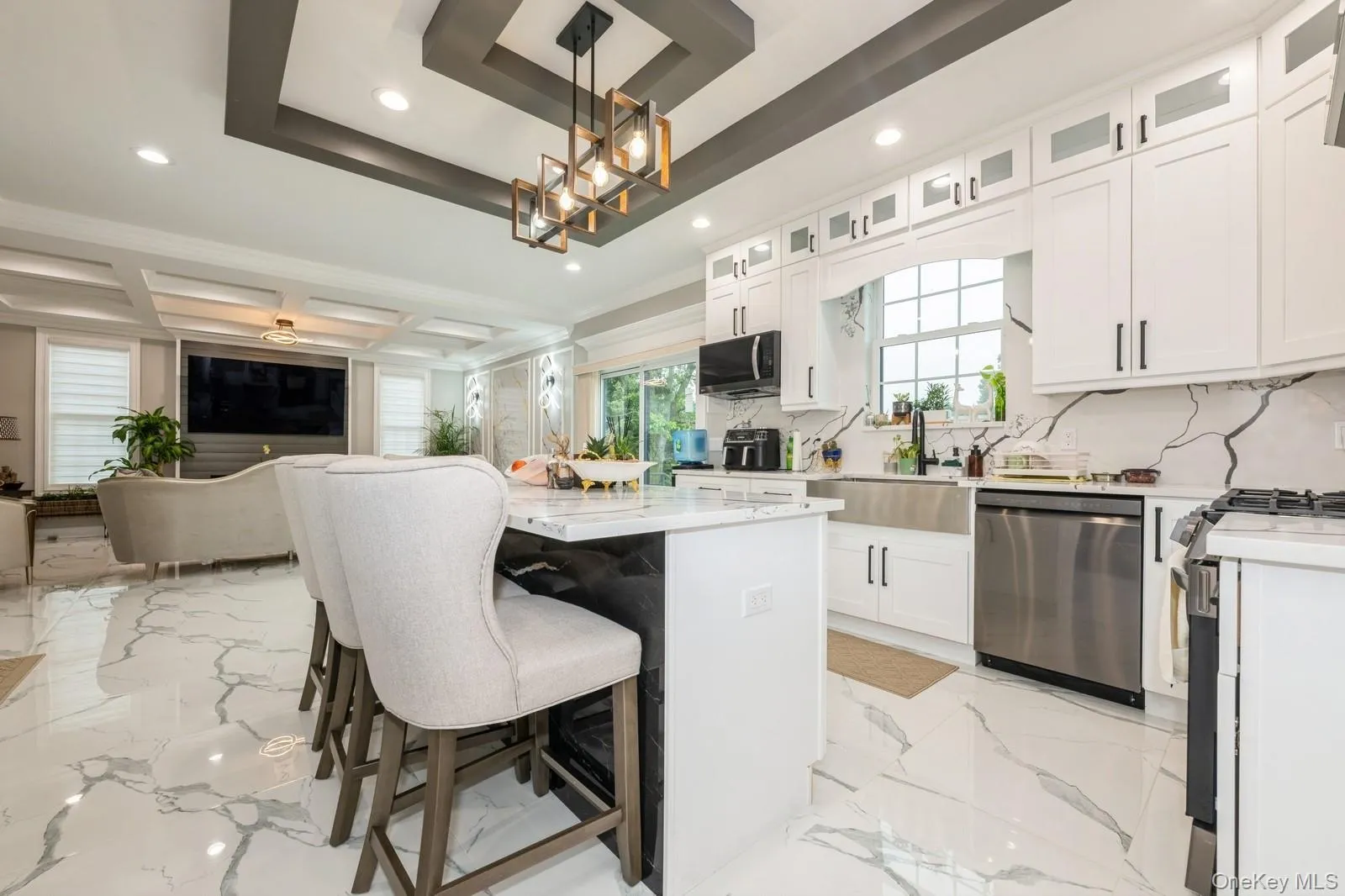 Kitchen featuring light stone countertops, glass insert cabinets, a breakfast bar, appliances with stainless steel finishes, and white cabinetry Kitchen featuring light stone countertops, glass insert cabinets, a breakfast bar, appliances with stainless steel finishes, and white cabinetry