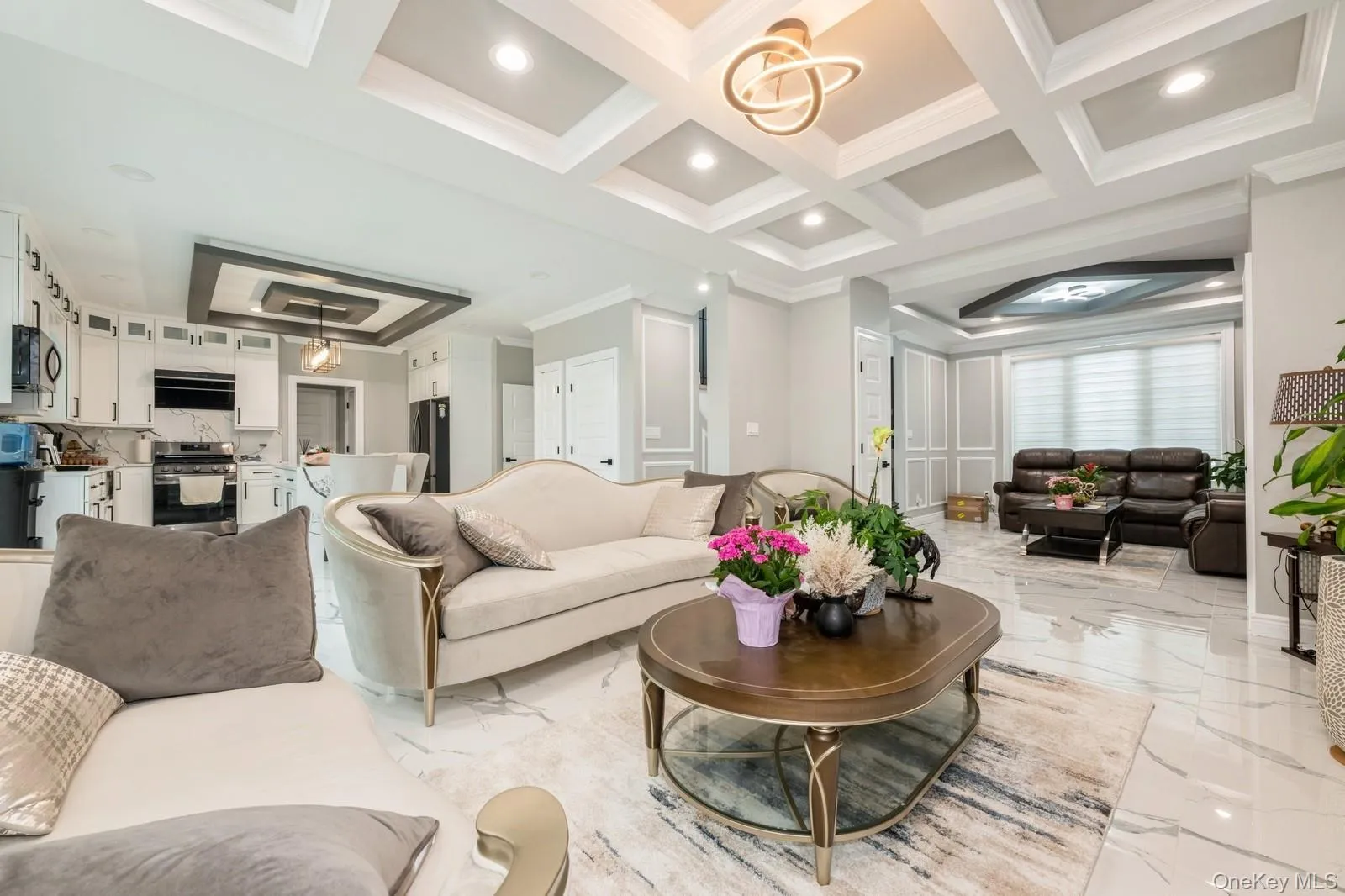 Living room featuring a chandelier, crown molding, light marble finish flooring, recessed lighting, and coffered ceiling Living room featuring a chandelier, crown molding, light marble finish flooring, recessed lighting, and coffered ceiling