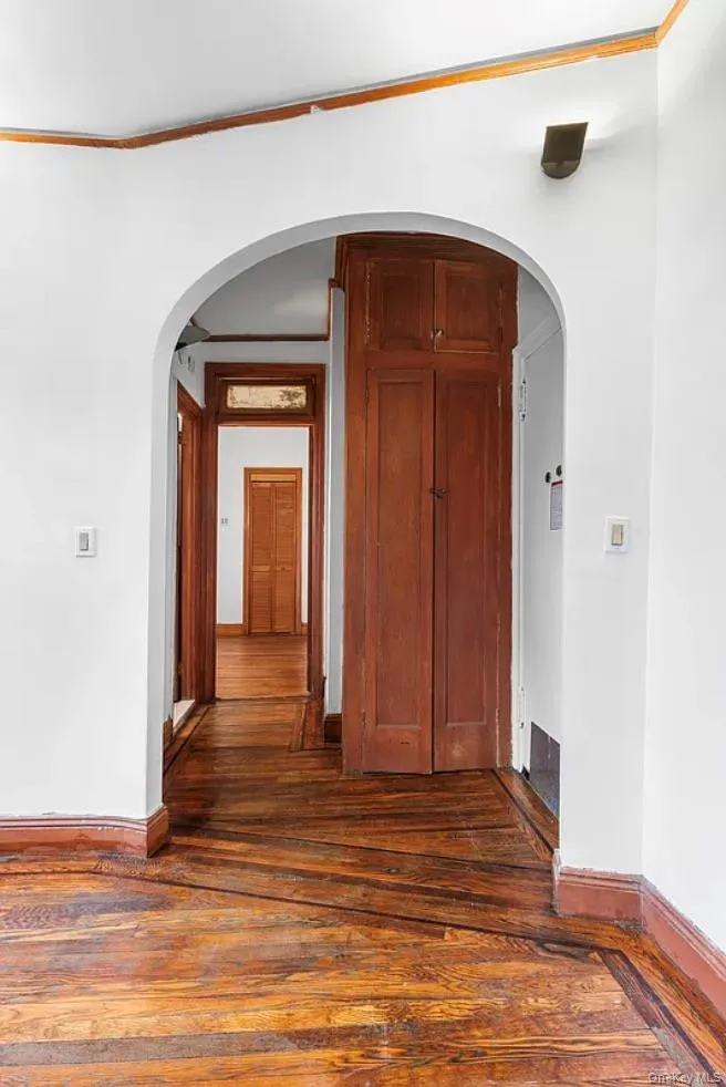 Hall featuring arched walkways and dark wood-style flooring Hall featuring arched walkways and dark wood-style flooring
