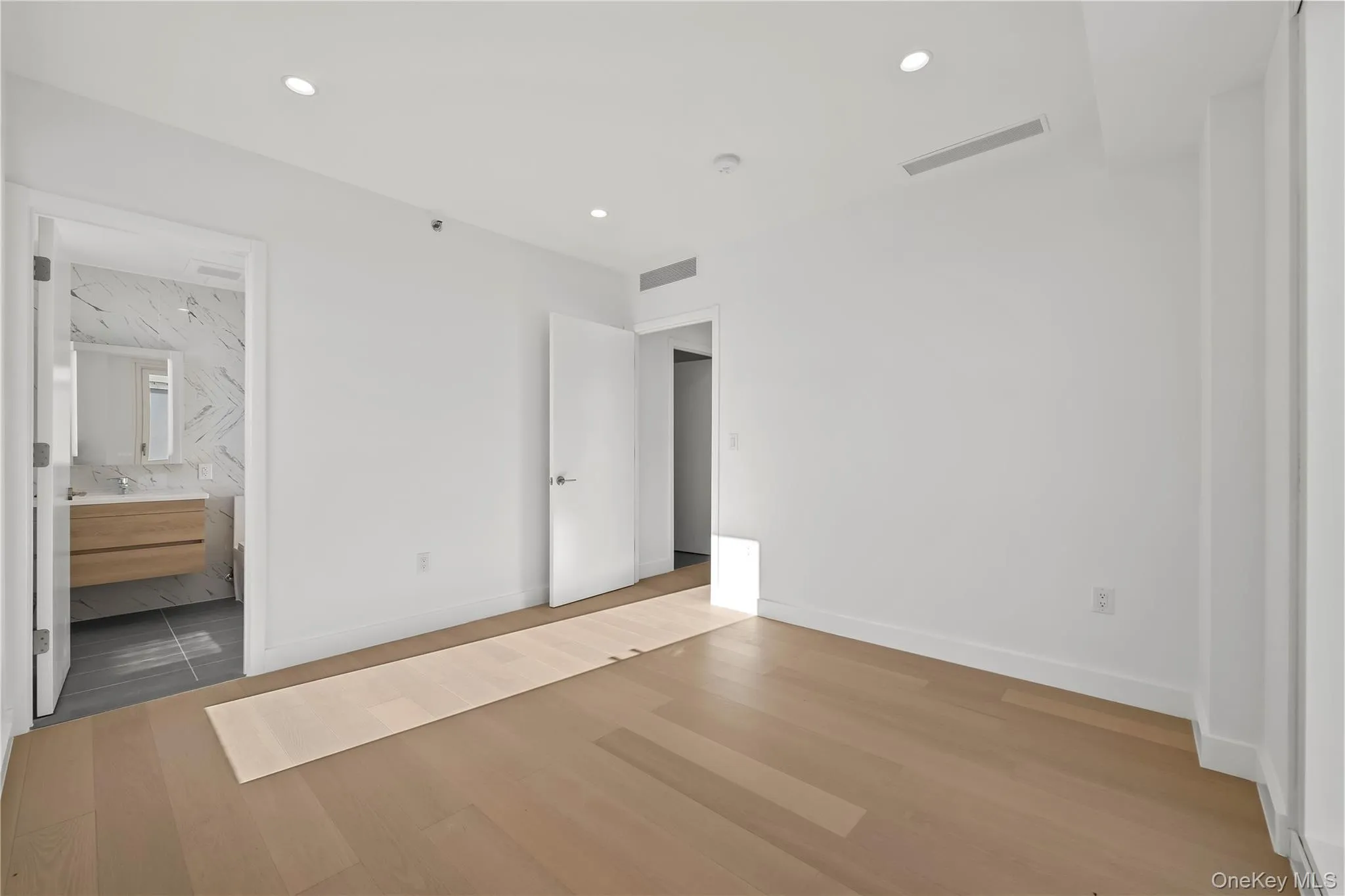 Unfurnished bedroom featuring wood finished floors, recessed lighting, and connected bathroom Unfurnished bedroom featuring wood finished floors, recessed lighting, and connected bathroom