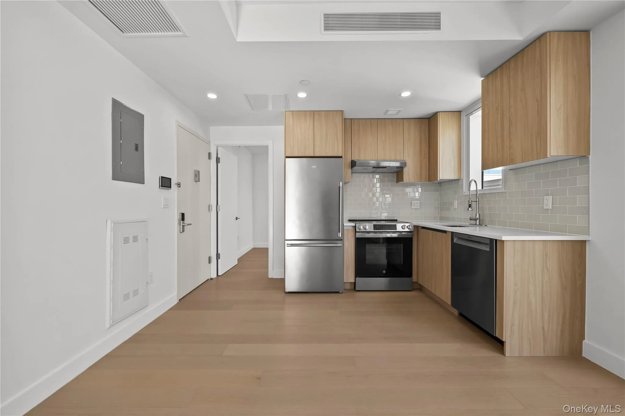 Kitchen featuring modern cabinets, stainless steel appliances, backsplash, light stone countertops, and light wood-style floors Kitchen featuring modern cabinets, stainless steel appliances, backsplash, light stone countertops, and light wood-style floors