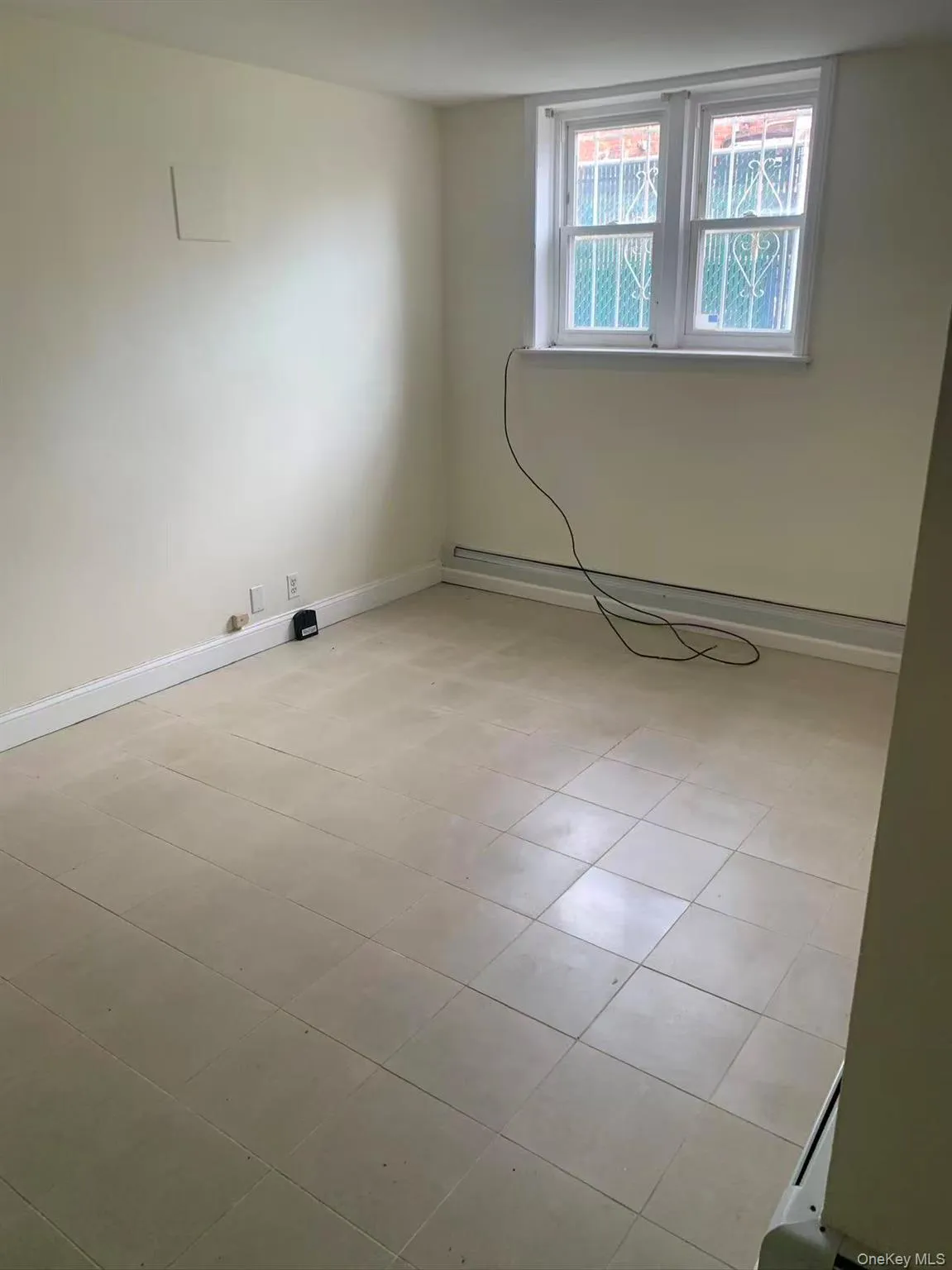 Empty room featuring a baseboard radiator and light tile patterned floors Empty room featuring a baseboard radiator and light tile patterned floors