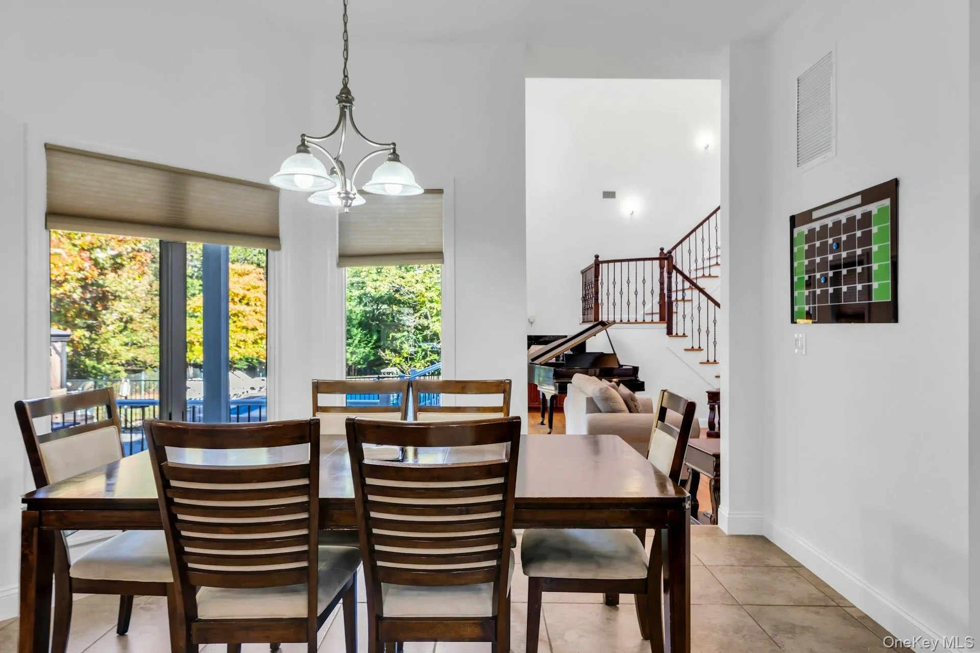 Dining area with stairs, a chandelier, light tile patterned floors, and a high ceiling