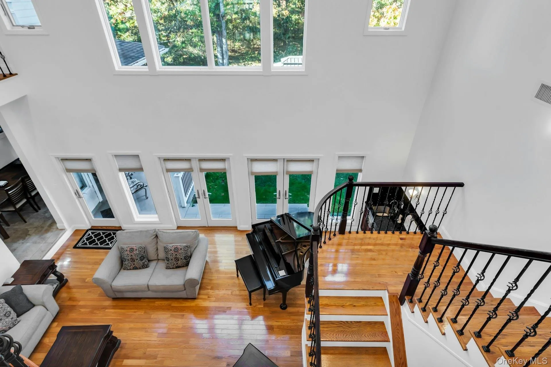 Living room with a high ceiling, french doors, hardwood / wood-style floors, and stairs