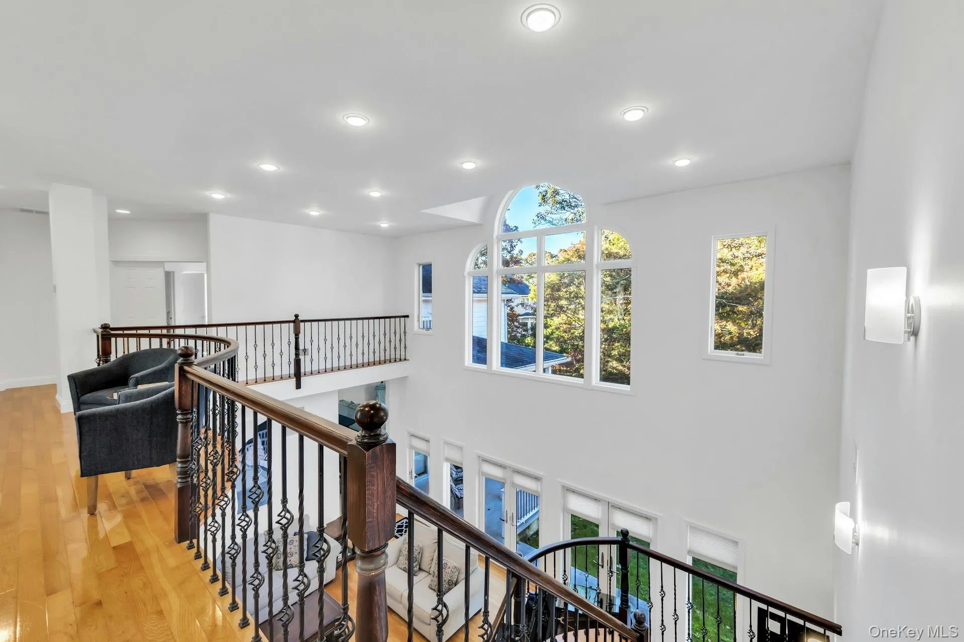 Corridor with healthy amount of natural light, hardwood / wood-style floors, recessed lighting, and an upstairs landing