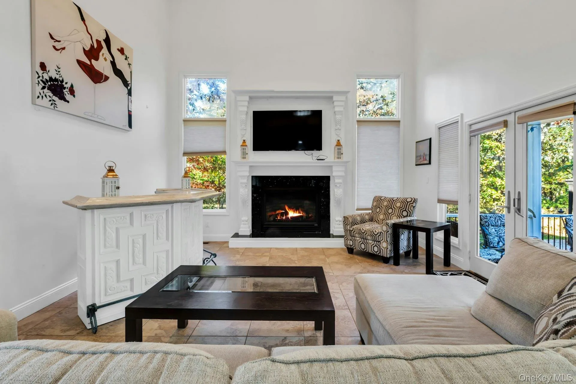 Tiled living area featuring a towering ceiling, a premium fireplace, and french doors