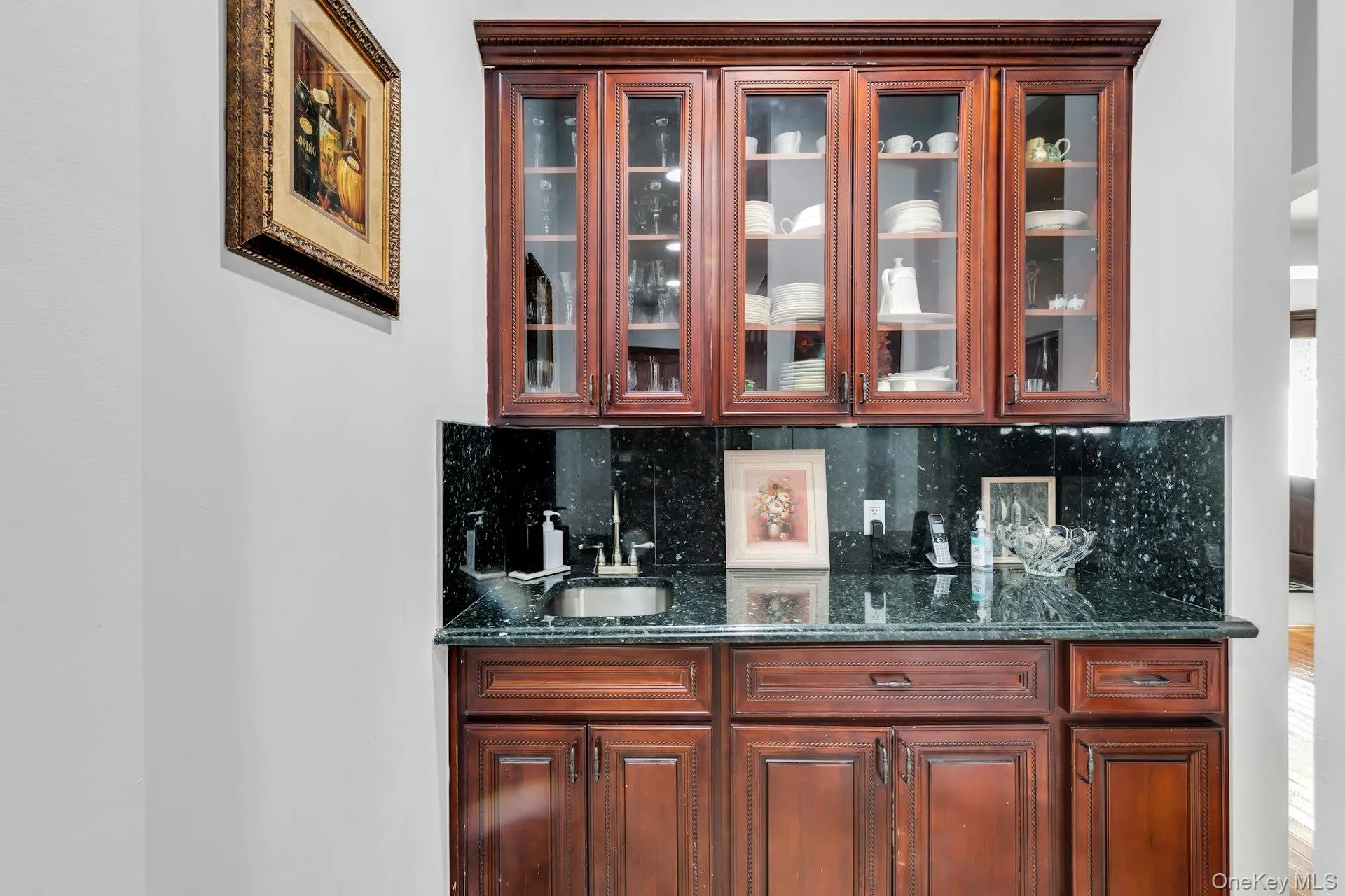 Indoor wet bar with dark stone countertops, glass insert cabinets, and tasteful backsplash