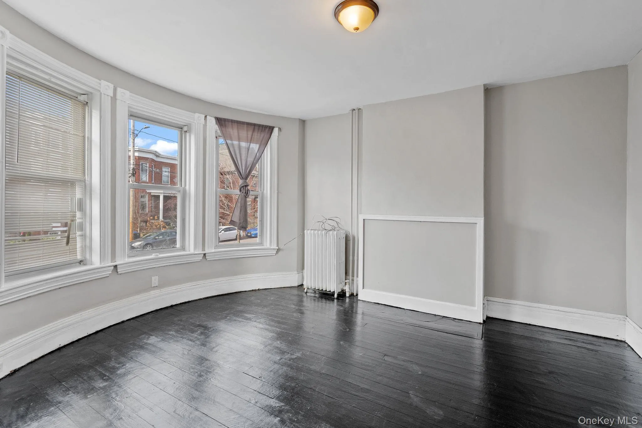 Unfurnished room with radiator heating unit and dark wood-style floors Unfurnished room with radiator heating unit and dark wood-style floors