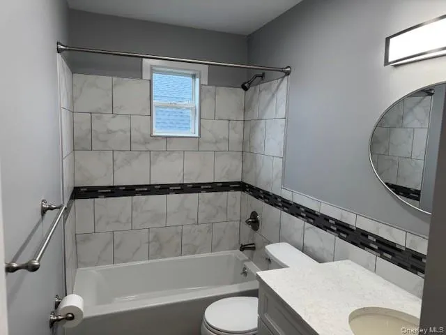 Bathroom with bathtub / shower combination, vanity, and tile walls Bathroom with bathtub / shower combination, vanity, and tile walls