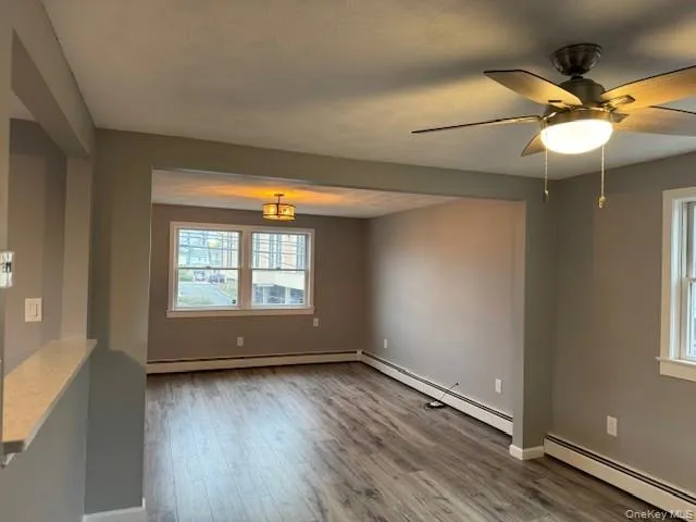 Spare room with a baseboard heating unit, wood finished floors, and a ceiling fan Spare room with a baseboard heating unit, wood finished floors, and a ceiling fan