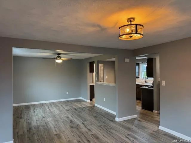Unfurnished room with light wood-style floors, a ceiling fan, and a textured ceiling Unfurnished room with light wood-style floors, a ceiling fan, and a textured ceiling