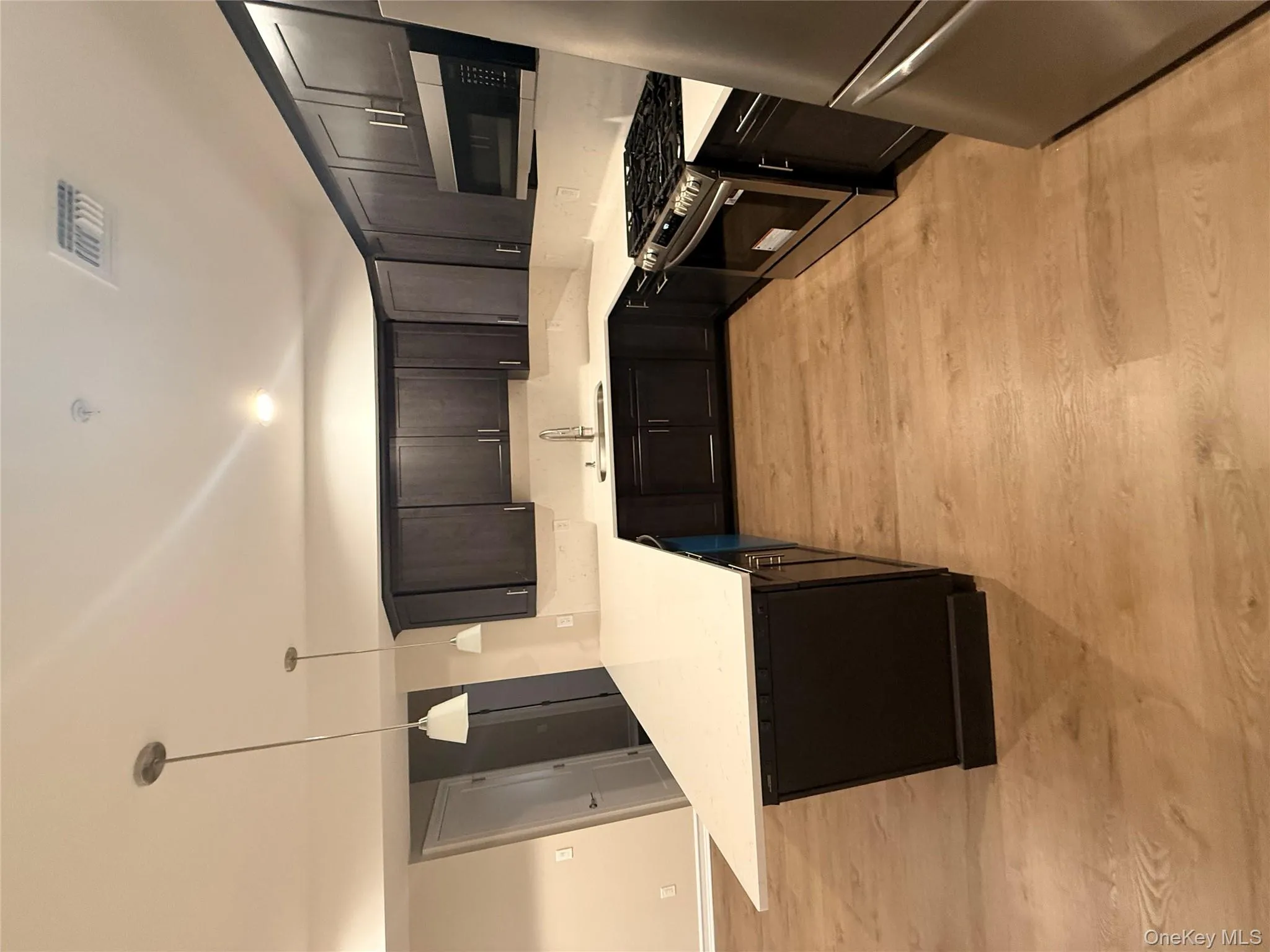 Kitchen featuring black range, fridge, pendant lighting, light stone countertops, and light wood finished floors Kitchen featuring black range, fridge, pendant lighting, light stone countertops, and light wood finished floors