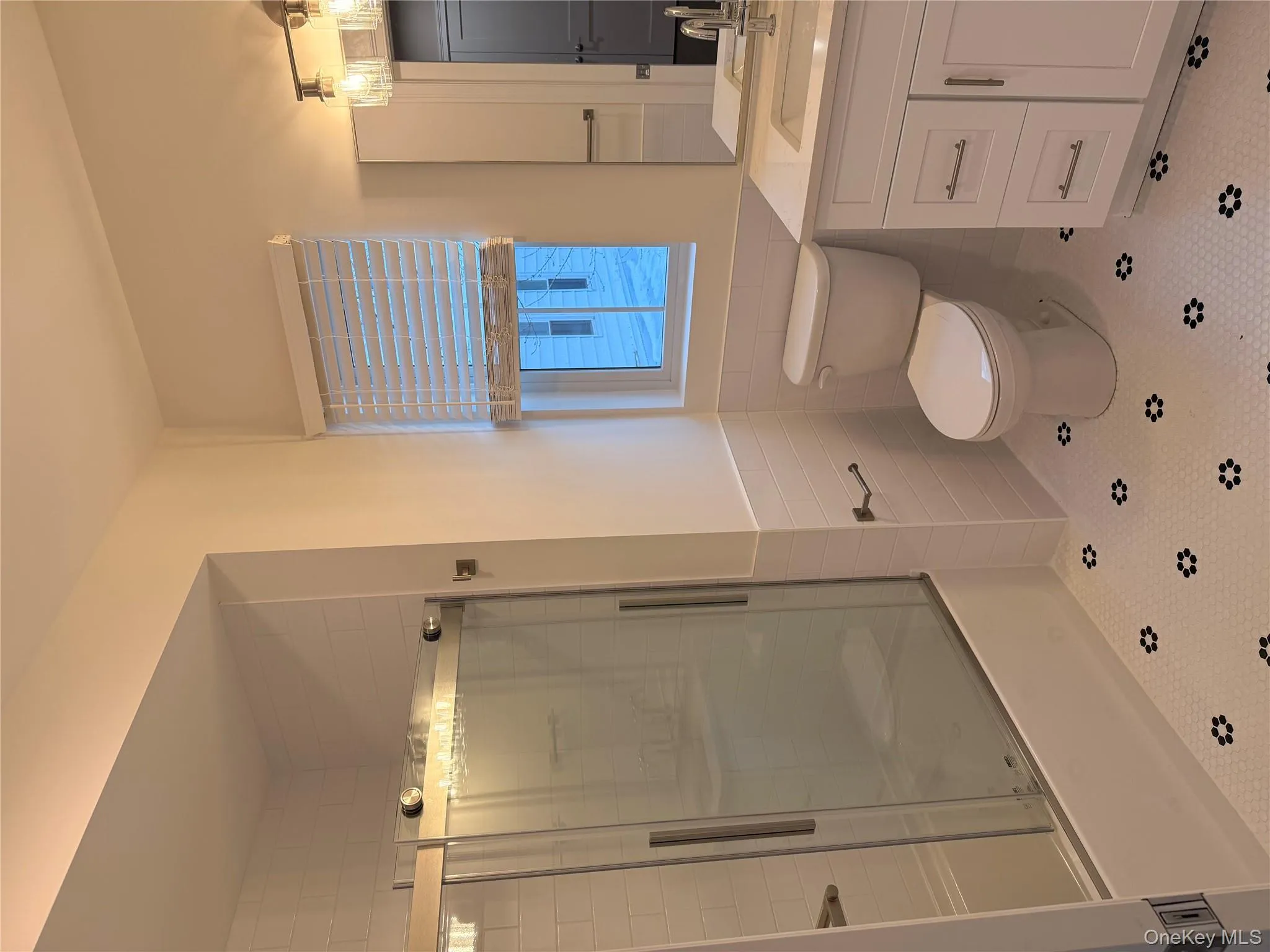 Bathroom with an enclosed shower, tile walls, vanity, wainscoting, and tile patterned flooring Bathroom with an enclosed shower, tile walls, vanity, wainscoting, and tile patterned flooring