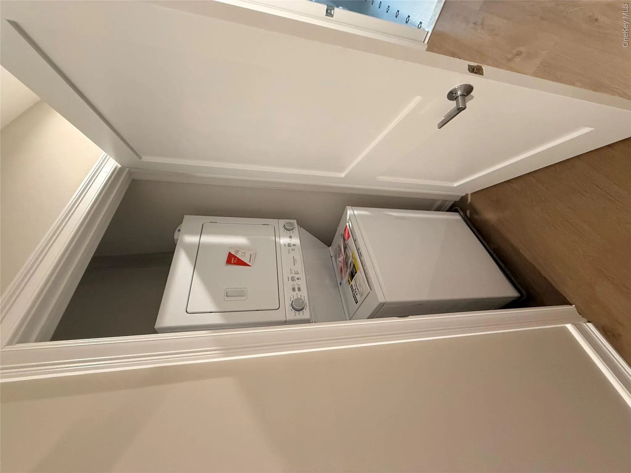 Washroom featuring wood finished floors and stacked washing machine and dryer Washroom featuring wood finished floors and stacked washing machine and dryer