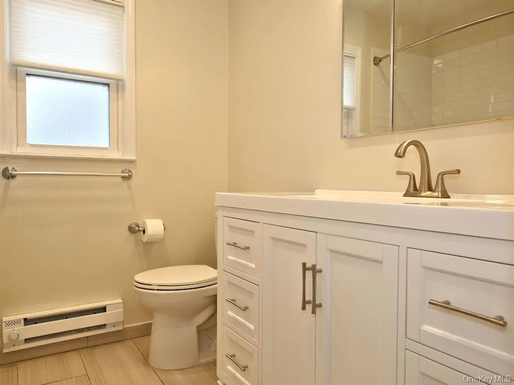 Full bath featuring a baseboard heating unit, vanity, and a shower Full bath featuring a baseboard heating unit, vanity, and a shower