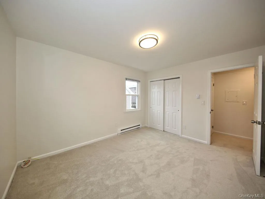 Unfurnished bedroom with a baseboard heating unit, a closet, and light colored carpet Unfurnished bedroom with a baseboard heating unit, a closet, and light colored carpet