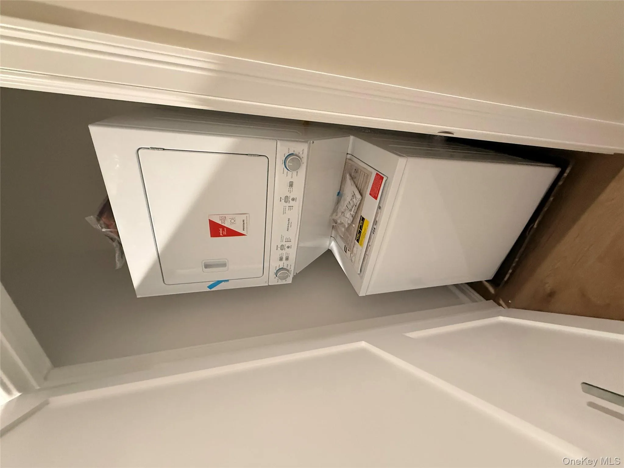 Laundry area featuring wood finished floors and stacked washer and clothes dryer Laundry area featuring wood finished floors and stacked washer and clothes dryer