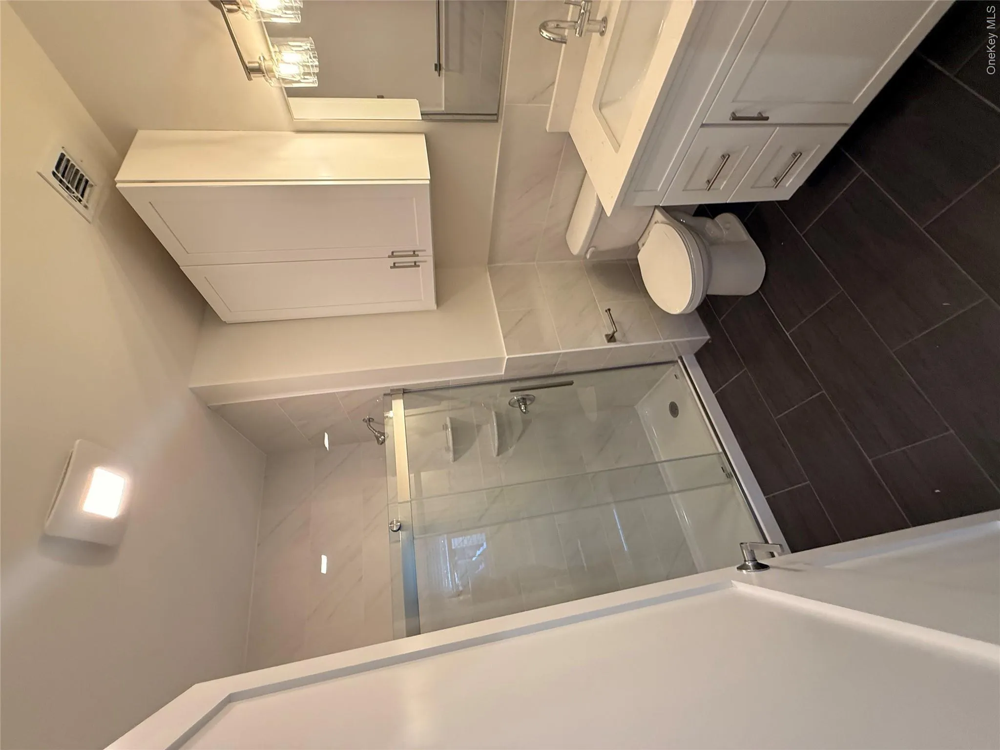 Bathroom featuring a shower stall, vanity, tile walls, and dark tile patterned floors Bathroom featuring a shower stall, vanity, tile walls, and dark tile patterned floors