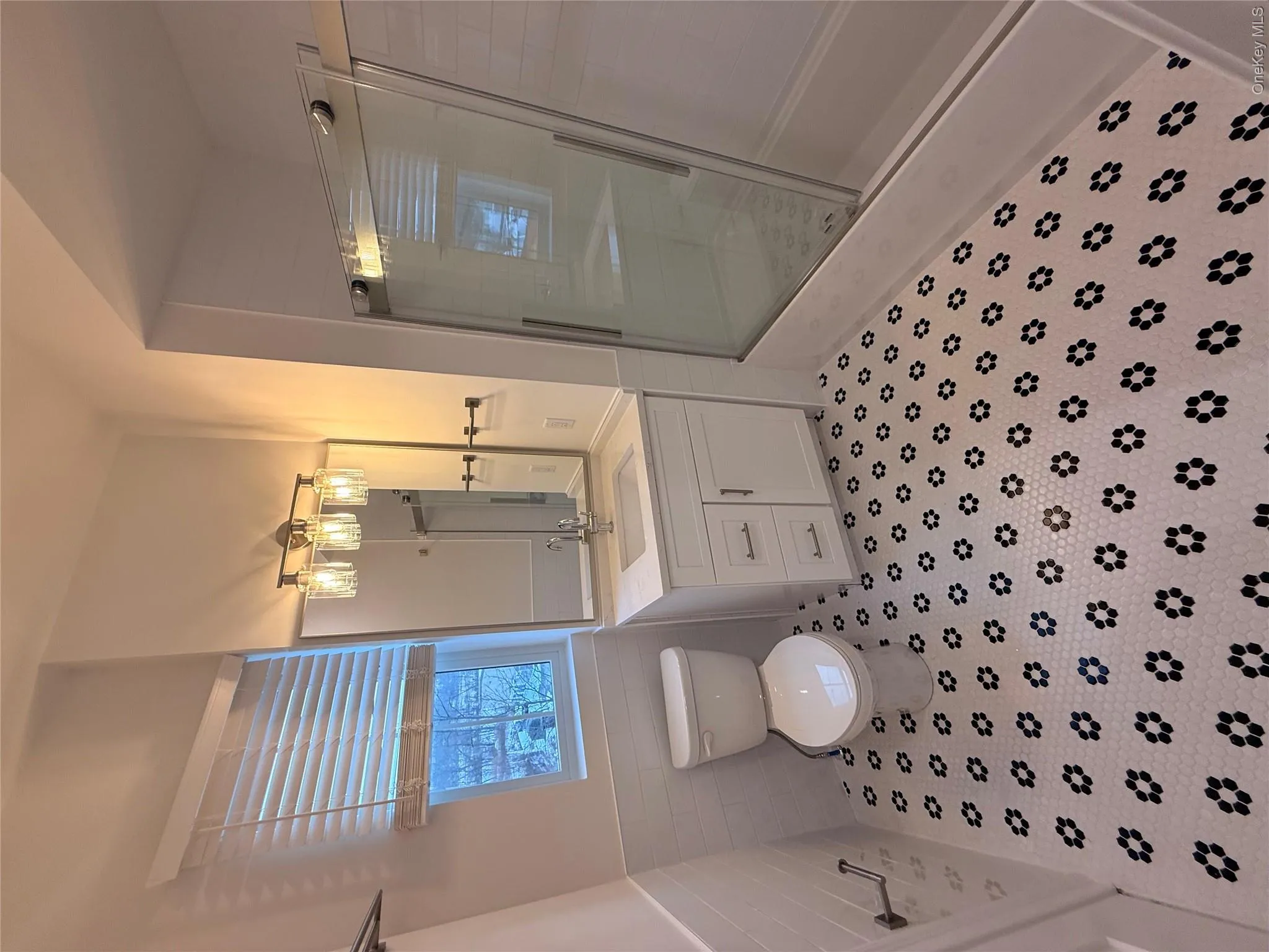 Bathroom featuring a shower stall, a wainscoted wall, vanity, and tile walls Bathroom featuring a shower stall, a wainscoted wall, vanity, and tile walls