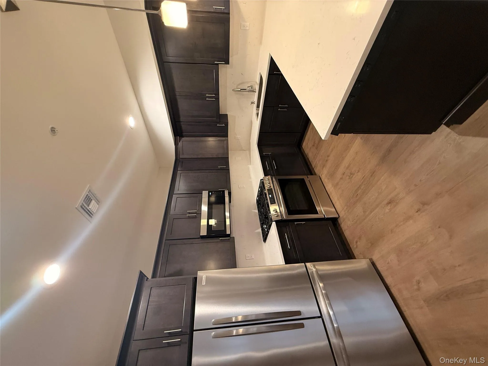 Kitchen with refrigerator, stainless steel range oven, pendant lighting, light stone countertops, and recessed lighting Kitchen with refrigerator, stainless steel range oven, pendant lighting, light stone countertops, and recessed lighting