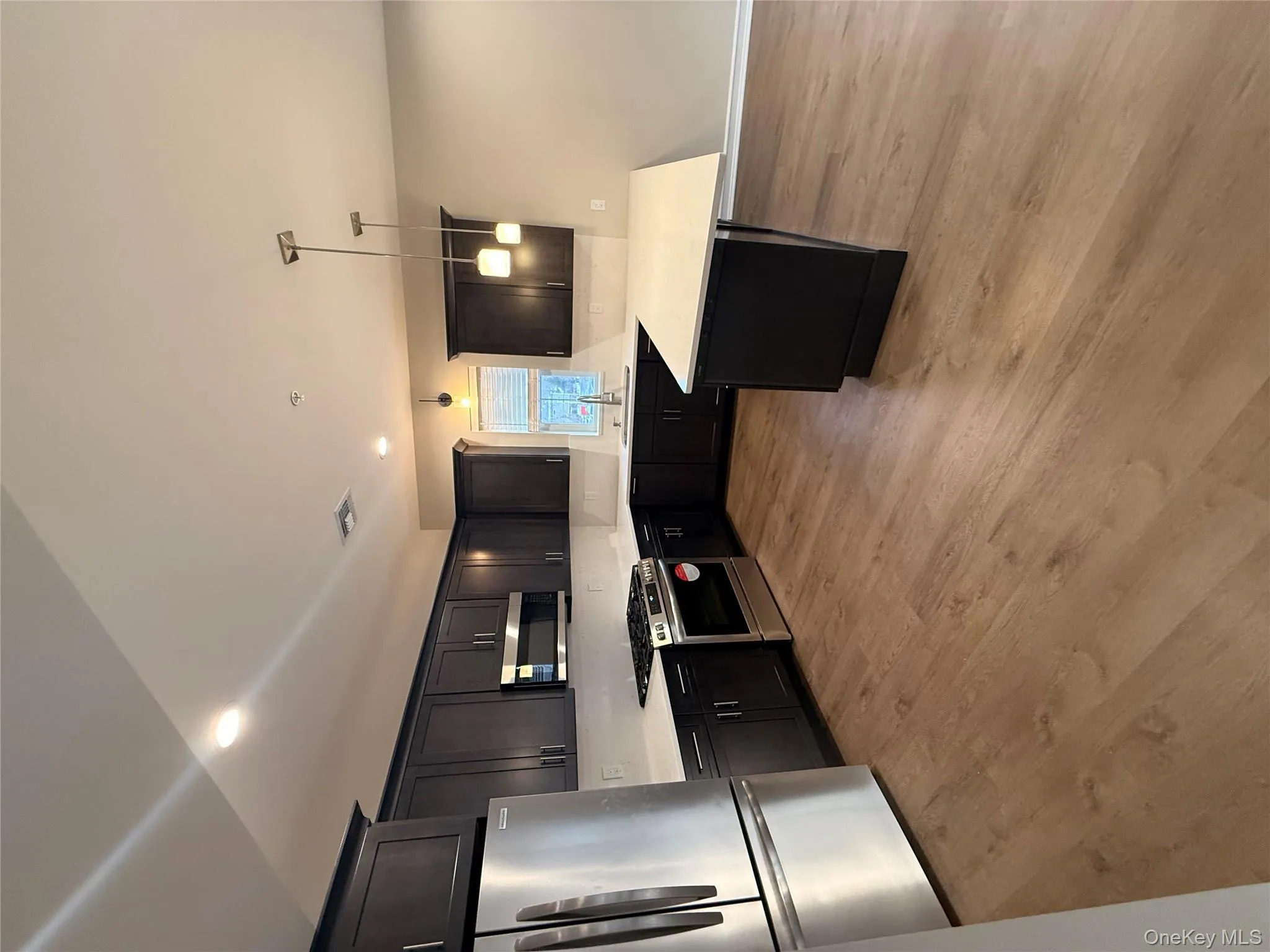 Kitchen featuring refrigerator, stainless steel stove, a peninsula, hanging light fixtures, and light wood finished floors Kitchen featuring refrigerator, stainless steel stove, a peninsula, hanging light fixtures, and light wood finished floors