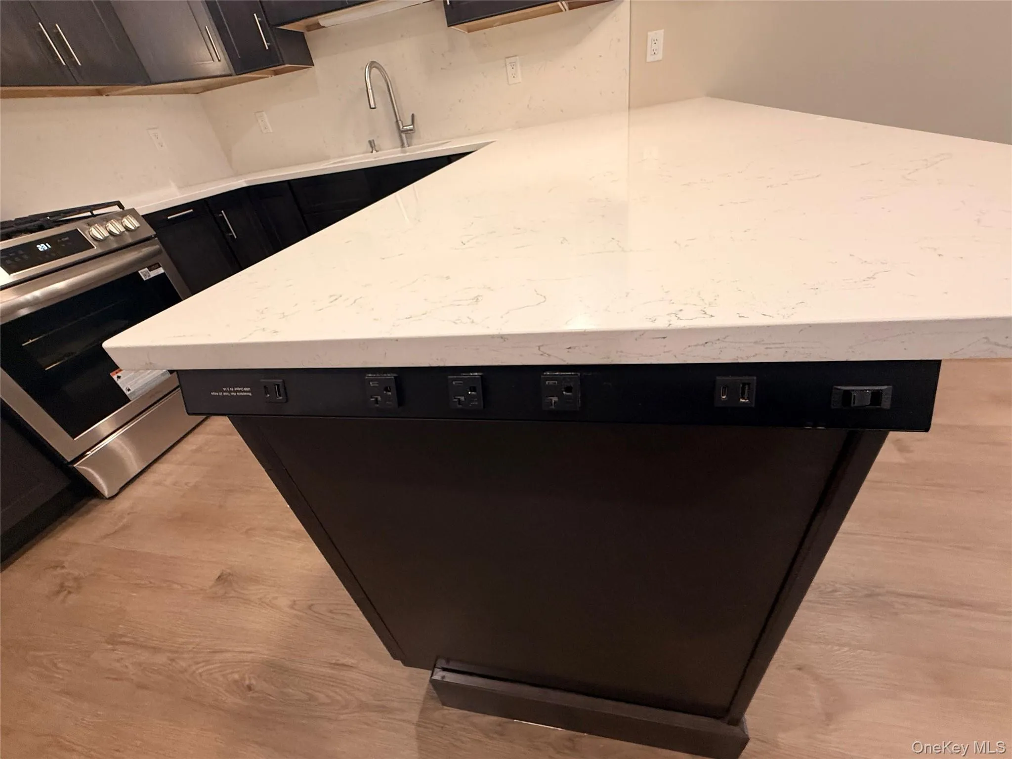 Kitchen with dishwasher, stainless steel range with gas stovetop, light stone countertops, and light wood-style floors Kitchen with dishwasher, stainless steel range with gas stovetop, light stone countertops, and light wood-style floors