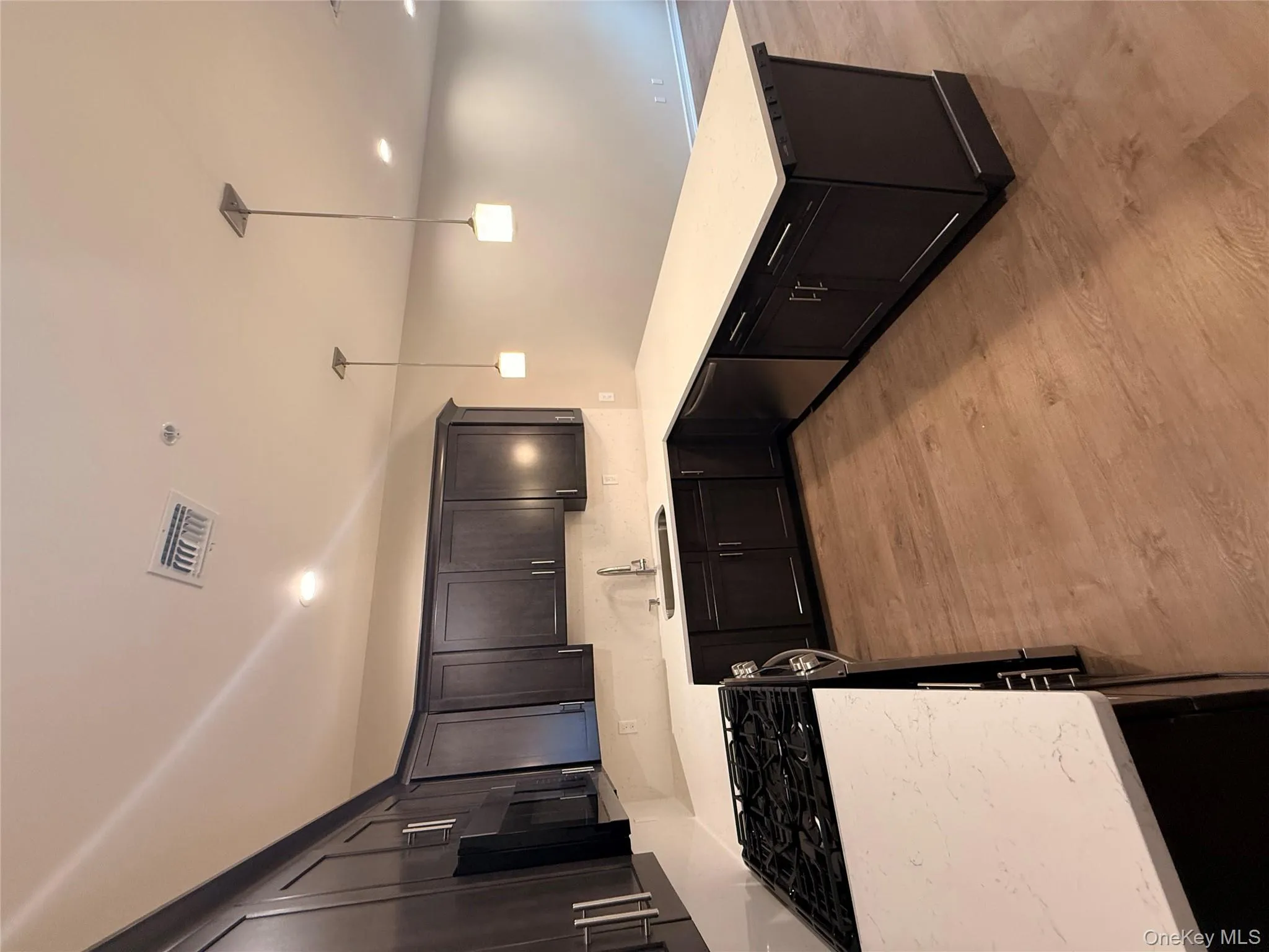 Kitchen featuring stove, pendant lighting, light stone counters, dishwashing machine, and light wood finished floors Kitchen featuring stove, pendant lighting, light stone counters, dishwashing machine, and light wood finished floors