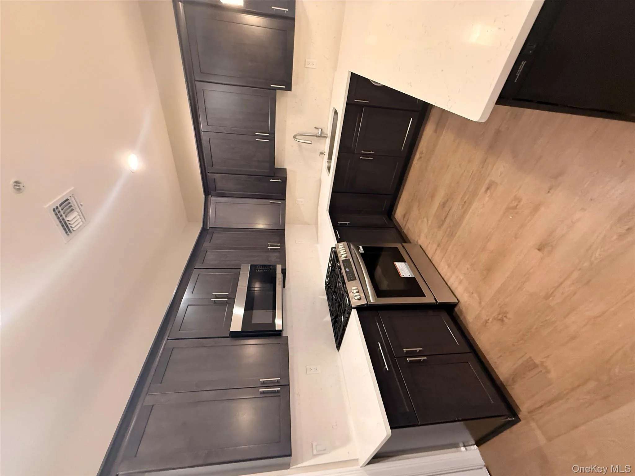 Kitchen with stainless steel range, light stone counters, light wood-style flooring, and recessed lighting Kitchen with stainless steel range, light stone counters, light wood-style flooring, and recessed lighting