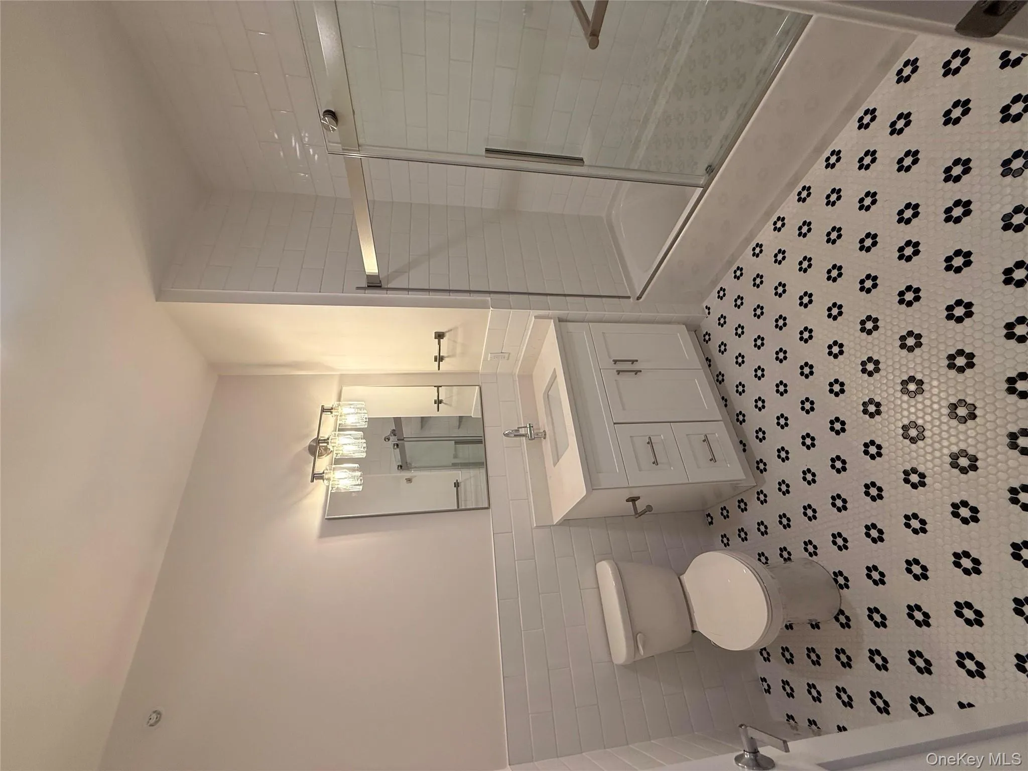Bathroom featuring tiled shower, vanity, tile walls, and wainscoting Bathroom featuring tiled shower, vanity, tile walls, and wainscoting
