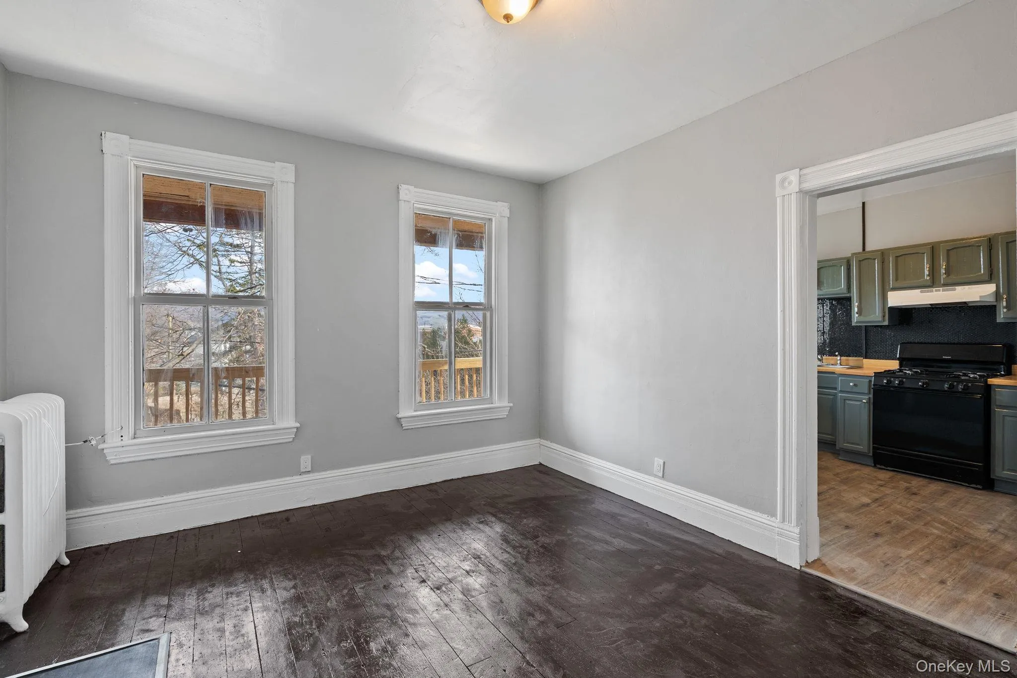 Unfurnished dining area featuring dark wood-type flooring and radiator heating unit Unfurnished dining area featuring dark wood-type flooring and radiator heating unit