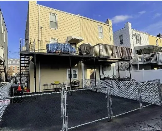 Rear view of property with a gate, a fenced front yard, a wooden deck, and stairway Rear view of property with a gate, a fenced front yard, a wooden deck, and stairway