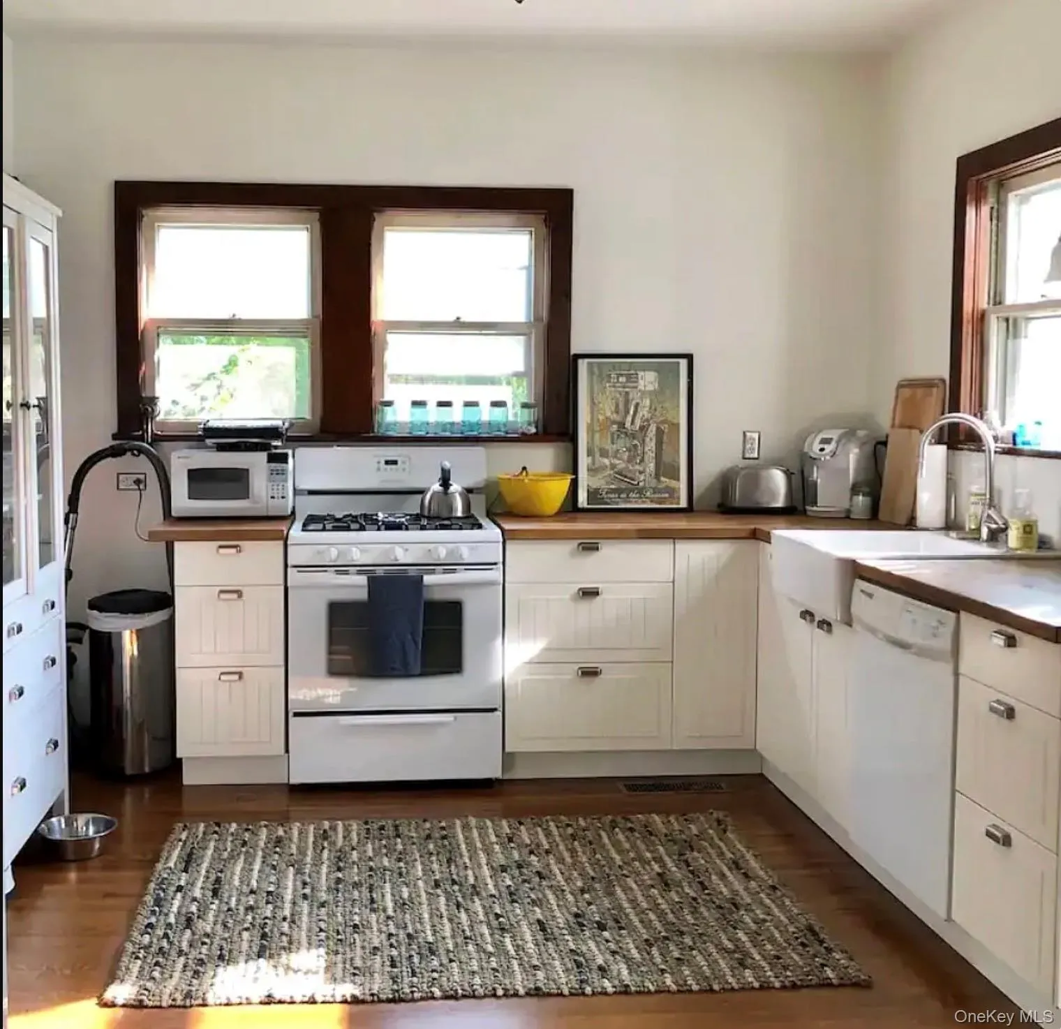 Kitchen featuring white appliances, white cabinetry, dark wood-type flooring, and butcher block countertops Kitchen featuring white appliances, white cabinetry, dark wood-type flooring, and butcher block countertops
