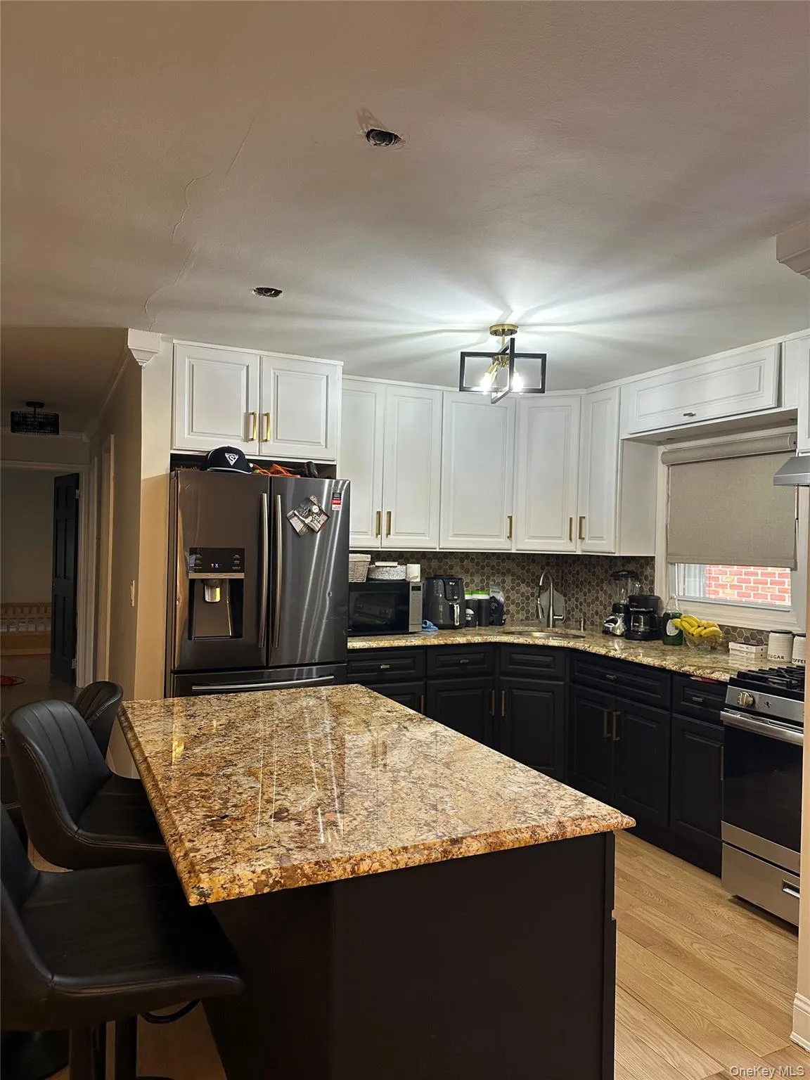 Kitchen featuring dark cabinets, white cabinetry, light stone countertops, and appliances with stainless steel finishes Kitchen featuring dark cabinets, white cabinetry, light stone countertops, and appliances with stainless steel finishes