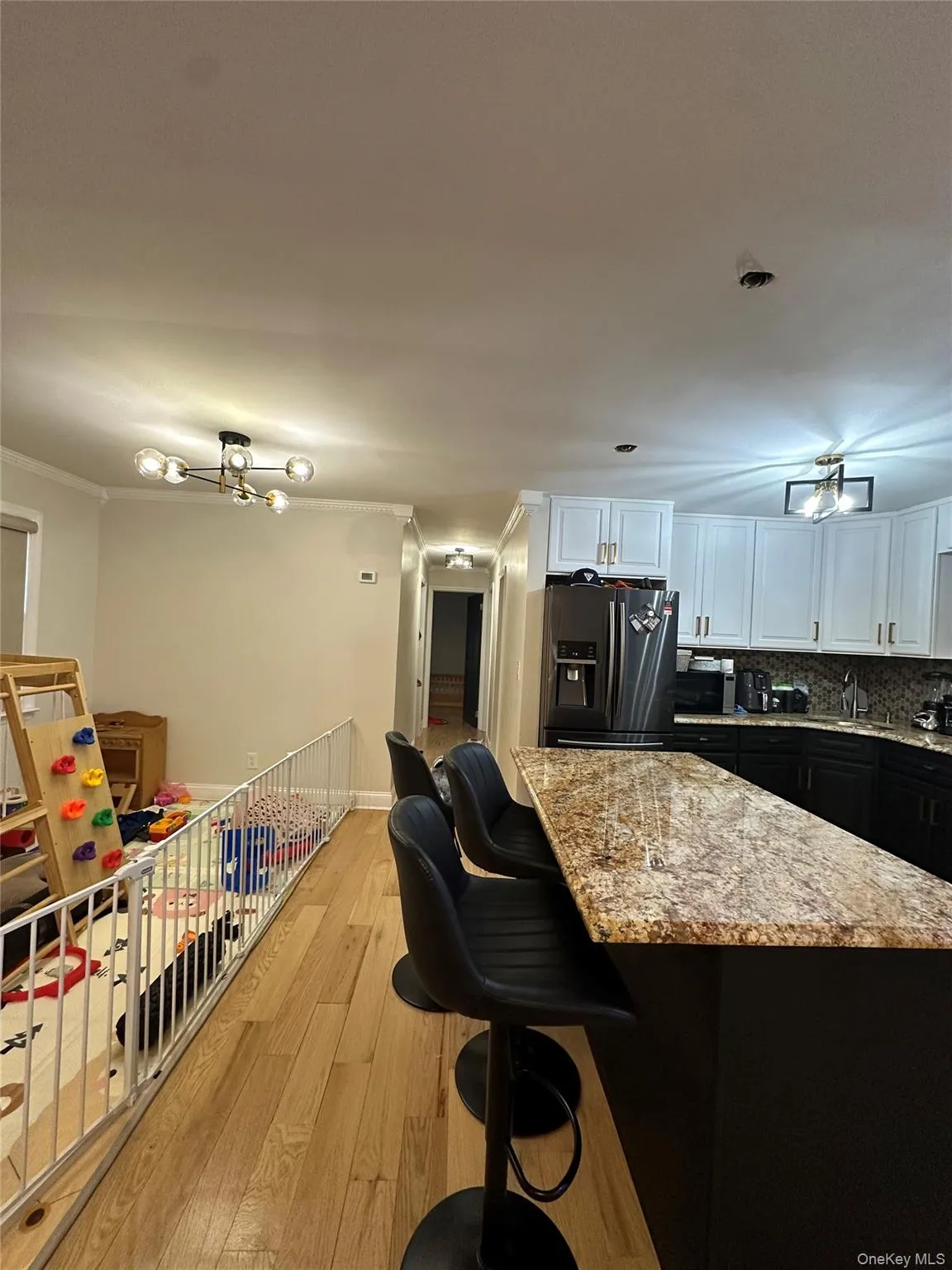 Kitchen with a breakfast bar, white cabinetry, light stone countertops, dark cabinets, and crown molding Kitchen with a breakfast bar, white cabinetry, light stone countertops, dark cabinets, and crown molding