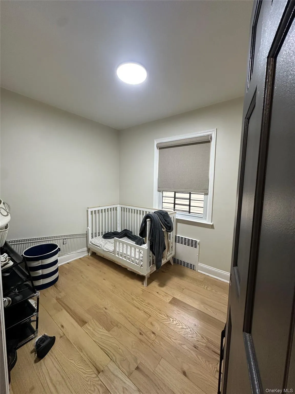 Bedroom featuring radiator and light wood finished floors Bedroom featuring radiator and light wood finished floors