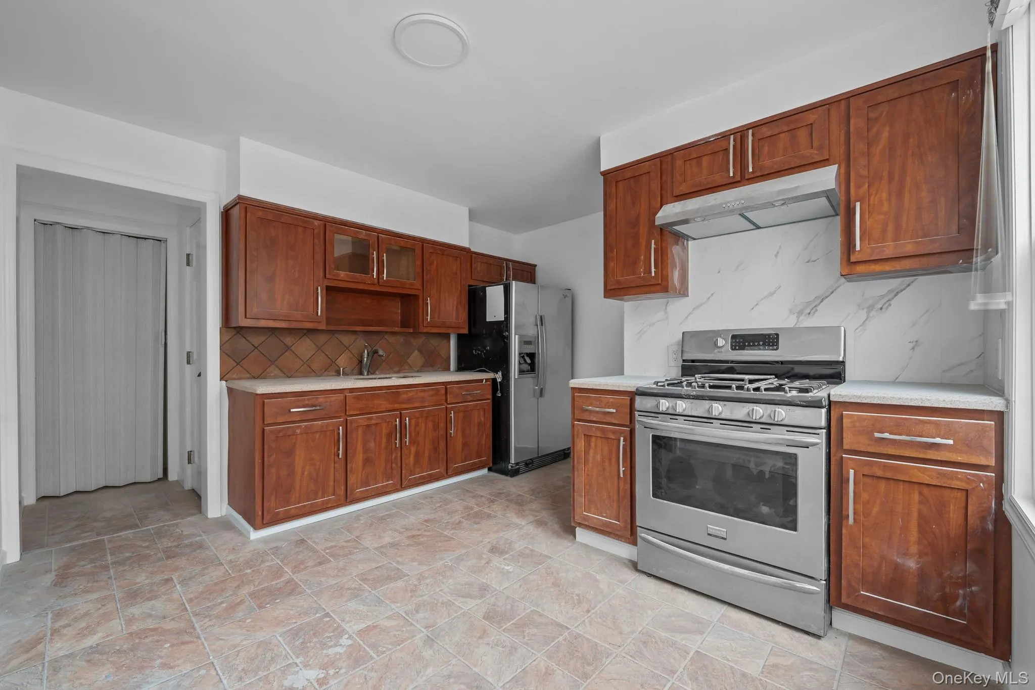 Kitchen with appliances with stainless steel finishes, light countertops, and under cabinet range hood Kitchen with appliances with stainless steel finishes, light countertops, and under cabinet range hood