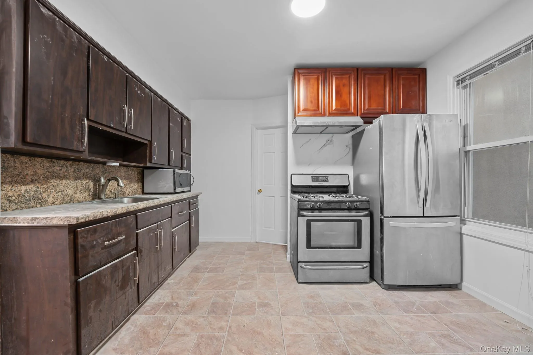 Kitchen with appliances with stainless steel finishes, dark brown cabinetry, tasteful backsplash, and light countertops Kitchen with appliances with stainless steel finishes, dark brown cabinetry, tasteful backsplash, and light countertops