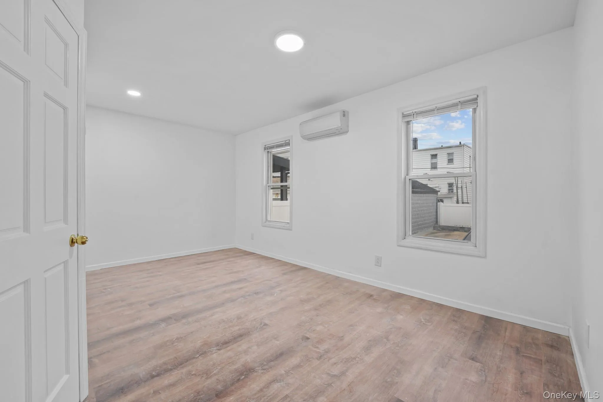 Empty room featuring light wood finished floors, a wall mounted AC, and recessed lighting Empty room featuring light wood finished floors, a wall mounted AC, and recessed lighting