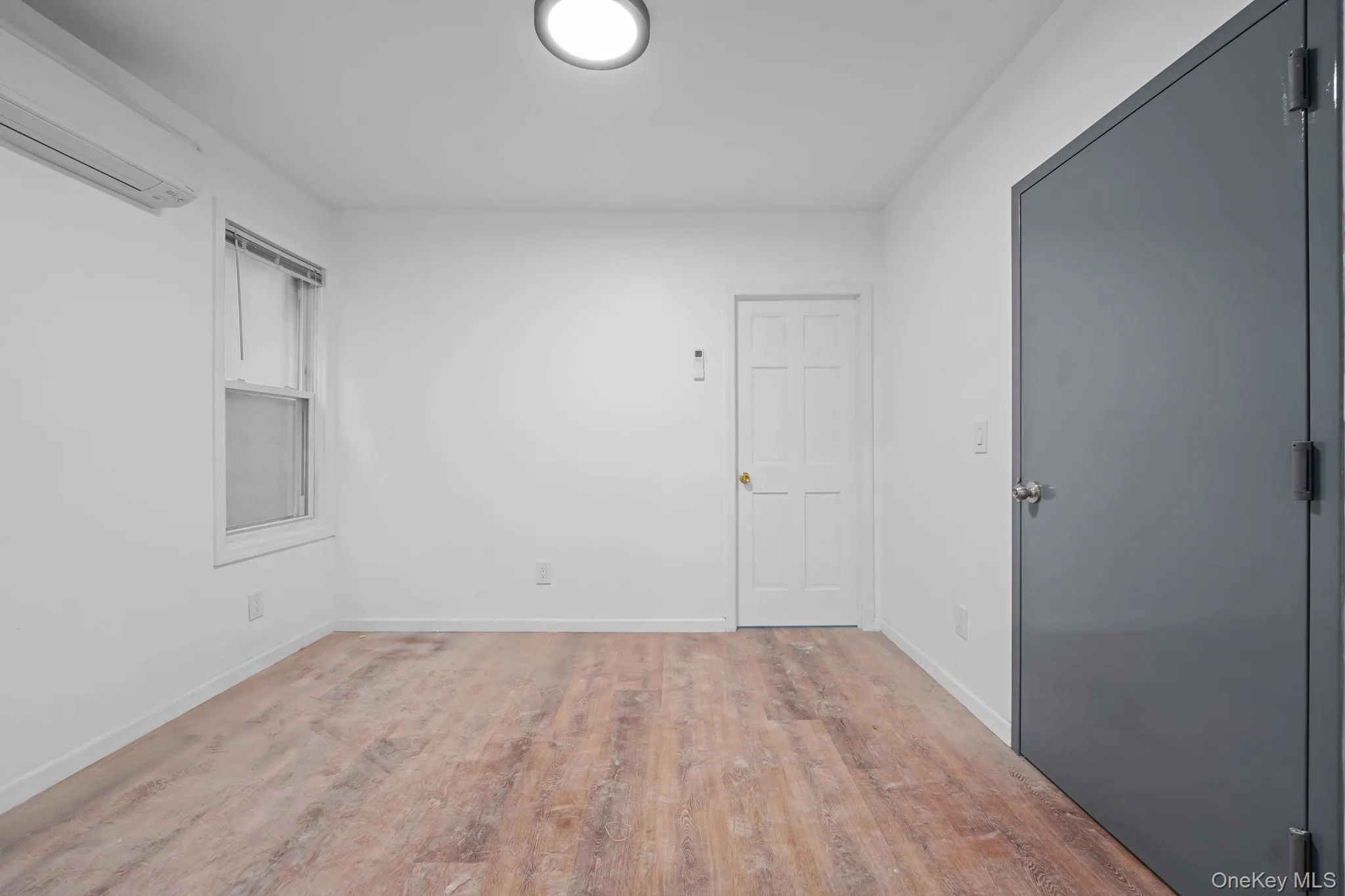 Empty room with a wall mounted air conditioner and wood finished floors Empty room with a wall mounted air conditioner and wood finished floors